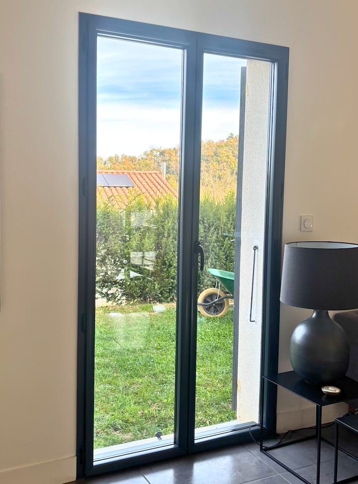 Porte-fenêtre ouvrant sur un jardin verdoyant.